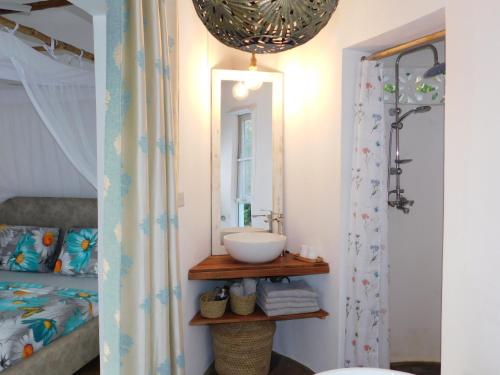 a bathroom with a sink and a mirror next to a bed at Dama Villa in Watamu