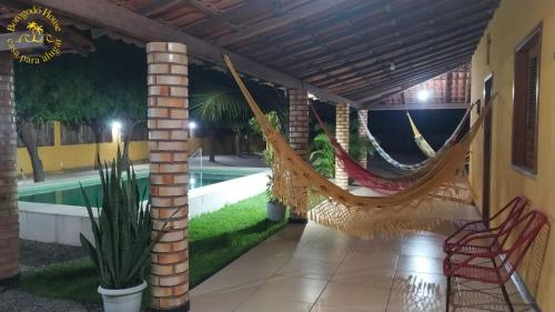 a patio with hammocks on a house with a pool at Borogodó House in Barra Grande