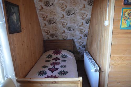a small bed in a room with a wall with roses at Śleboda wynajem pokoi Ewa Satoła in Biały Dunajec