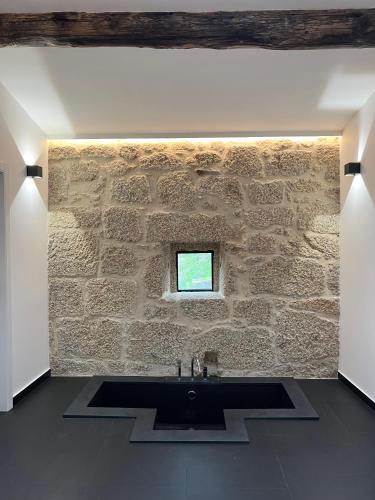 a stone walled bathroom with a sink and a window at Quinta da Porta - Solar de Vale de Prazeres in Vale de Prazeres