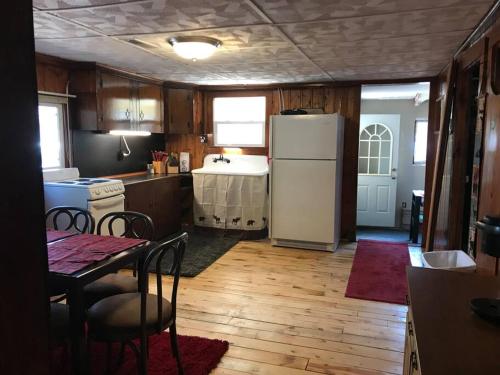 a kitchen with a table and a white refrigerator at Royce’s Outpost Rustic cabin nearby trails in Mio