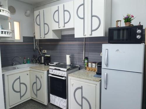 a kitchen with white cabinets and a white refrigerator at Your ¥achting Home in Sousse