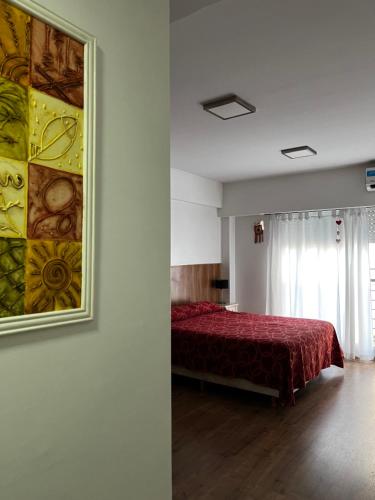 Un dormitorio con una cama roja y una pintura en la pared en MIKA APART HOSPITAL ITALIANO en Buenos Aires