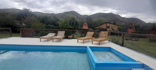 a swimming pool with lounge chairs and a swimming pool at Complejo de Cabañas Tierra de Luna in Potrerillos
