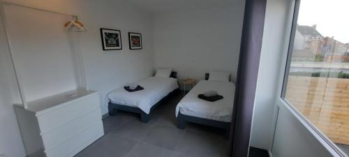 Una pequeña habitación con dos camas y una ventana. en Duplex appartement 4-6 pers La Traction Avant, en Ostende