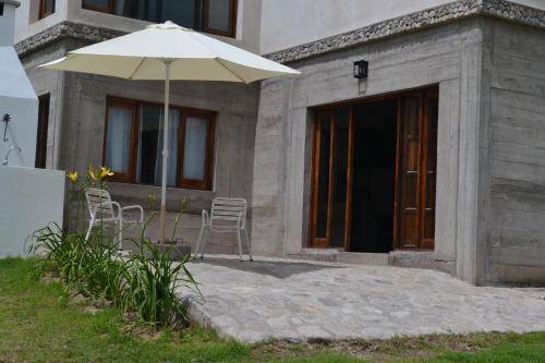 a patio with an umbrella and chairs in front of a building at Aires del Alto - casas in Tafí del Valle