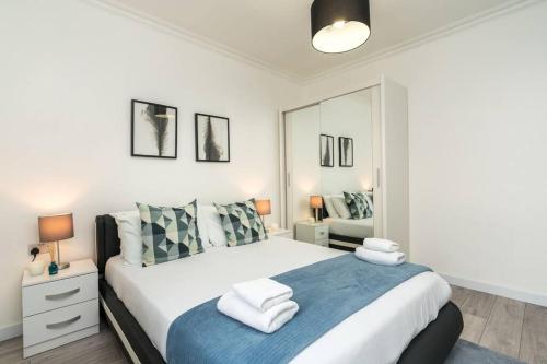 a white bedroom with a large bed with blue blanket at Superb flat close to super famous Portobello Road in London