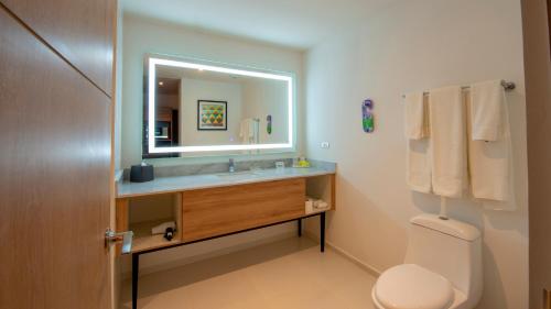 a bathroom with a sink and a mirror and a toilet at Holiday Inn & Suites - Merida La Isla by IHG in Mérida