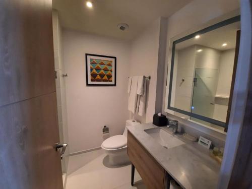 a bathroom with a sink and a toilet and a mirror at Holiday Inn & Suites - Merida La Isla by IHG in Mérida