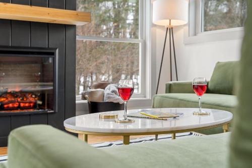 two glasses of red wine on a table in a living room with a fireplace at Launchpoint Lodge in Lincoln
