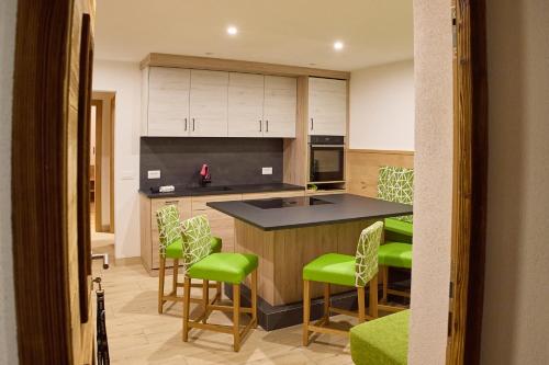 une cuisine avec des tabourets verts et un comptoir dans l'établissement GSCNARA - APARTMENT LIN, à Antermoia
