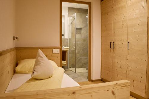 - une chambre avec un lit et une douche en verre dans l'établissement GSCNARA - APARTMENT LIN, à Antermoia
