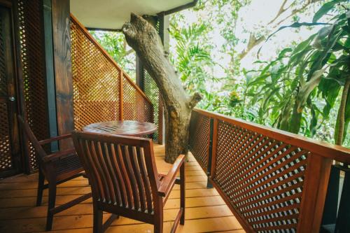 a porch with two chairs and a table and a tree at Hotel Bosque del Mar Playa Hermosa in Playa Hermosa
