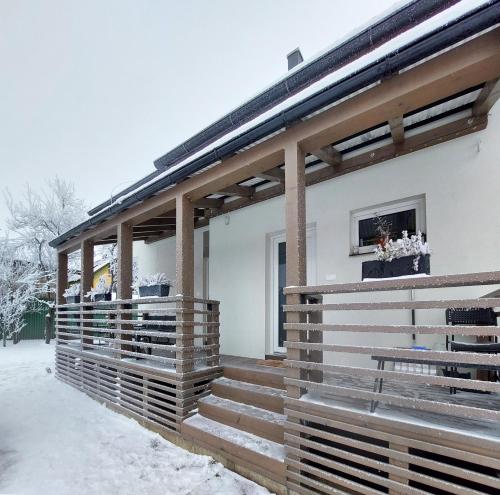 a house with a wooden facade in the snow at Apartmány Lučina in Veľký Slavkov