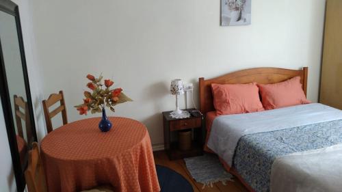 a bedroom with a bed and a table with a vase on it at Hostal Patrimonial Angelmó in Puerto Montt