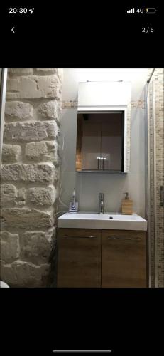 baño con lavabo y pared de piedra en Jean-Marie en París