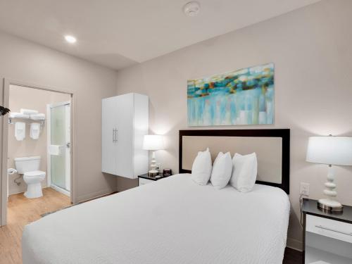 a bedroom with a white bed and a bathroom at WaterWalk Raleigh RTP in Durham