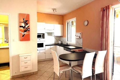 een keuken met een zwarte tafel en witte stoelen bij Studio cosy avec vue mer in Ajaccio