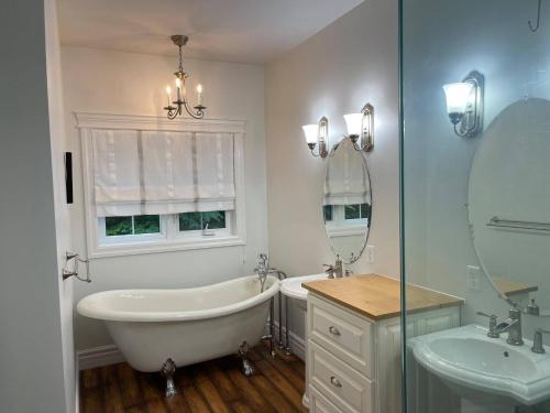 uma casa de banho branca com uma banheira e um lavatório em WELCOME TO BURNT RIVER ESTATE em Kawartha Lakes