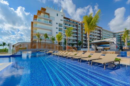a swimming pool with chairs and a building at Royalton Splash Riviera Cancun, An Autograph Collection All-Inclusive Resort in Cancún