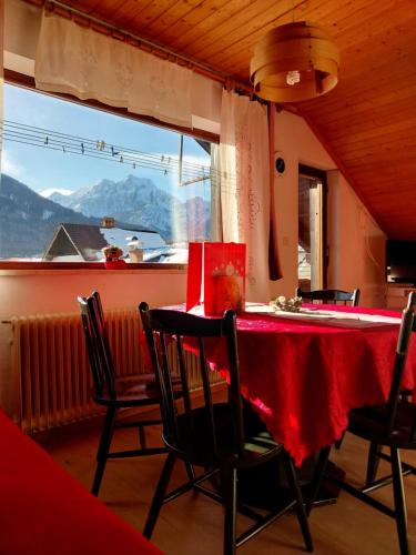 comedor con mesa roja, sillas y ventana en APARTMA 27, en Kranjska Gora