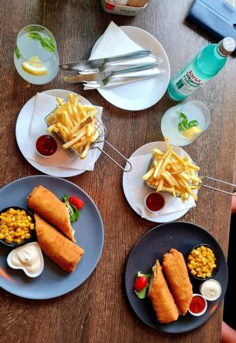 a table topped with plates of food and french fries at Gajeva Rooms - Stockholm apartment SELF CHECK-IN in Virovitica