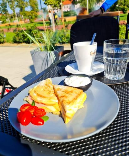 a white plate with a sandwich and tomatoes on a table at Gajeva Rooms - Stockholm apartment SELF CHECK-IN in Virovitica