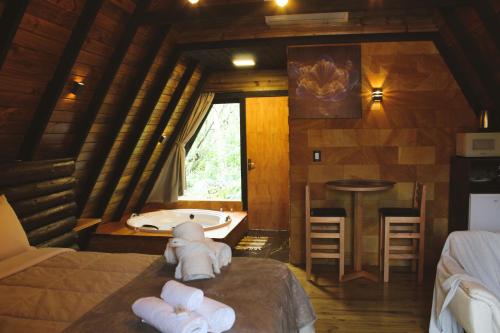 a bathroom with a tub and a bed with towels at Pousada Índios Coroados in Praia Grande