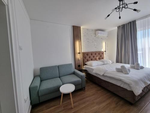 een slaapkamer met een bed en een blauwe bank bij M Lux Apartments in Banja Luka