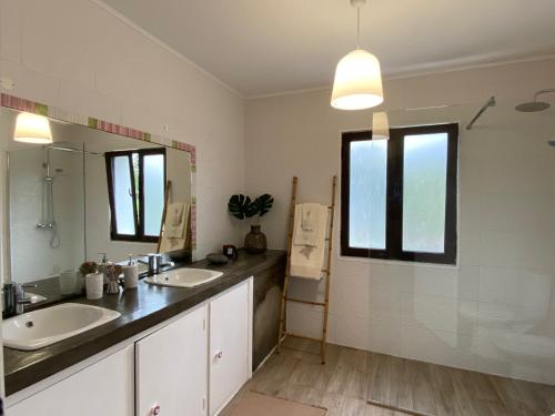 een badkamer met 2 wastafels en een grote spiegel bij Casa das Hortências by Azoresrent in Farroupo