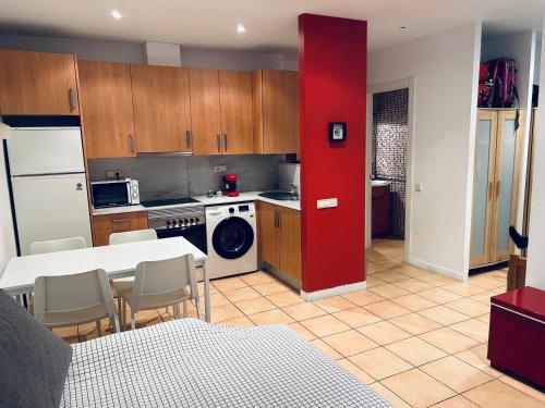 uma cozinha com uma mesa branca e uma parede vermelha em Céntrico apartamento a 150 metros de la playa. Parking* em Lloret de Mar