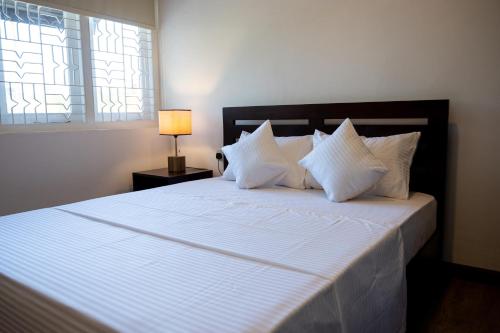 a bed with white sheets and pillows in a bedroom at Avega Urban - Colombo 07 in Colombo