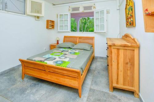 um quarto com uma cama de madeira e uma secretária de madeira em AGREABLE VILLA DU DIAMANT em Le Diamant