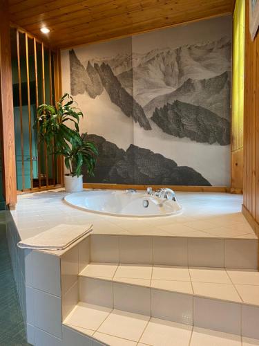 La salle de bains est pourvue d'une baignoire avec une plante en pot. dans l'établissement LE CLOS DU TULIPIER, à La Chapelle-du-Bard
