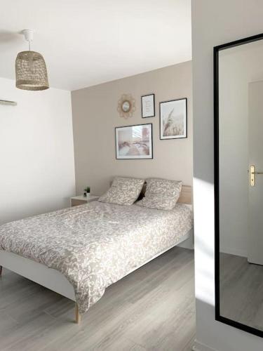 een witte slaapkamer met een bed en een spiegel bij Grand F3 à 30mn de Paris - Terrasse + Parking privé in Saint-Ouen-lʼAumône
