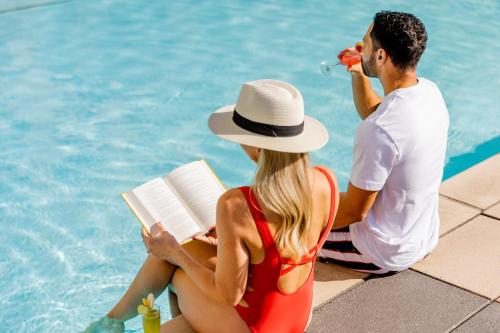 a man and woman sitting next to a swimming pool at Omni San Diego Hotel in San Diego