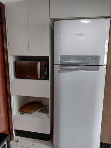 a refrigerator with a microwave in a kitchen at Apartamento no coração de Poços de Caldas in Poços de Caldas