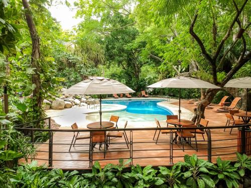 una terraza de madera con mesas y sombrillas junto a una piscina en Hotel Bosque del Mar Playa Hermosa en Playa Hermosa