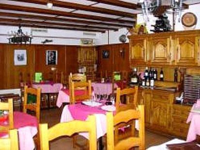 a dining room with tables and chairs and a kitchen at Logis de la Licorne in La Ferrière