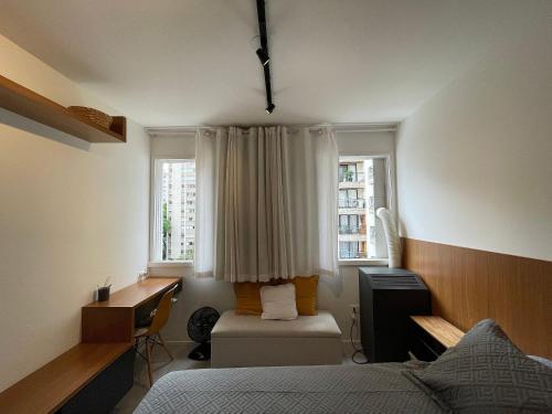 1 dormitorio con cama, escritorio y ventana en Conforto e praticidade próximo à Oscar Freire, en São Paulo