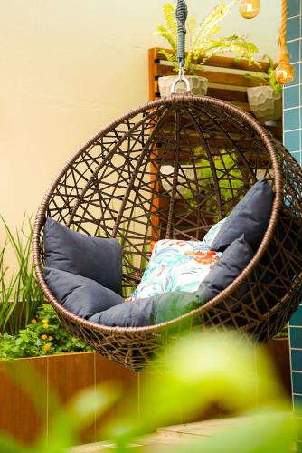 a hanging basket chair with pillows in a garden at Pousada Marítimos in Maragogi