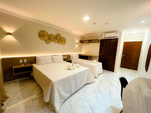 a hotel room with two beds and a table at Pousada Marítimos in Maragogi