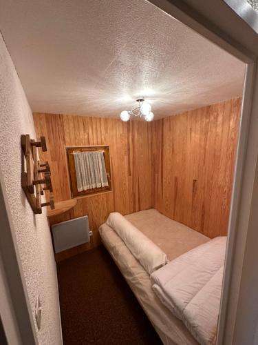 ein kleines Schlafzimmer mit einem Bett in einem Zimmer mit Holzwänden in der Unterkunft Appartement Les Carroz d'Araches 4 à 6 couchages in Les Carroz d'Araches