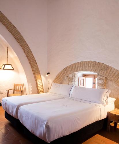 a bedroom with a large white bed in a room at Hotel Tugasa Convento San Francisco in Vejer de la Frontera
