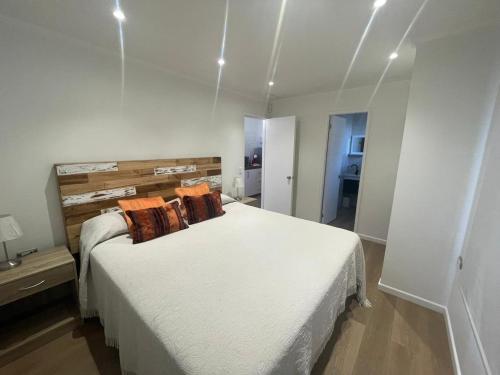 1 dormitorio con 1 cama blanca grande con almohadas de color naranja en Casa nueva de playa 3D 2B en El Quisco