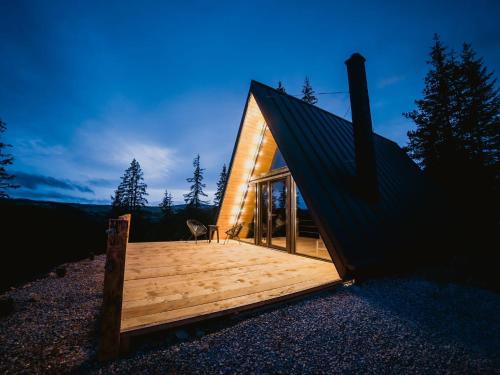 a small cabin with a deck in the woods at La KOLTAU A-Frame in Mărişel