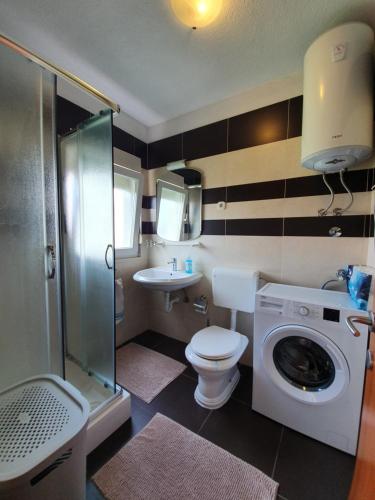 y baño con aseo, lavabo y lavadora. en Apartments Petani en Zadar