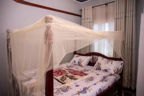 a bed with a canopy in a bedroom at Yobo's Complex Guest House in Kampala