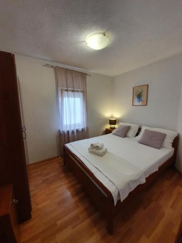 a bedroom with a large white bed with a window at Apartments Petani in Zadar