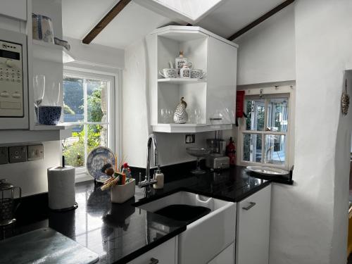 a kitchen with black counter tops and a sink at Beautiful Cottage near Harlech with ocean views in Llanfair